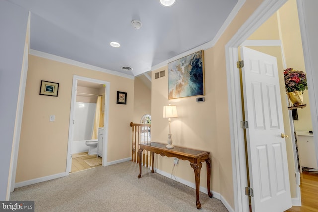 hallway with baseboards, visible vents, carpet floors, and ornamental molding