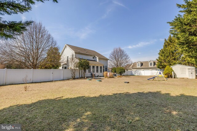 view of yard featuring a storage shed, an outdoor structure, a playground, and a fenced backyard