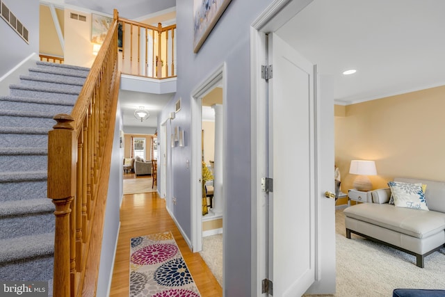 interior space with light wood-type flooring, visible vents, crown molding, and stairway