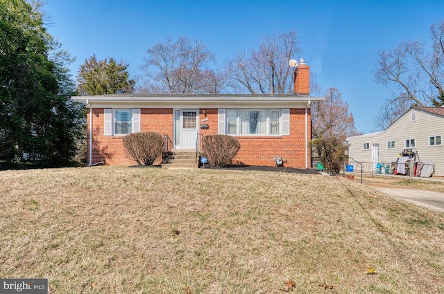 view of front of property with brick siding, entry steps, a chimney, and a front yard