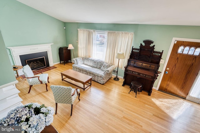 living room with a fireplace with flush hearth, wood finished floors, and baseboards