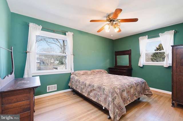 bedroom featuring visible vents, a ceiling fan, baseboards, and hardwood / wood-style flooring