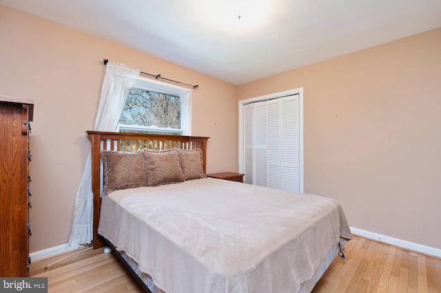 bedroom featuring a closet, baseboards, and light wood finished floors