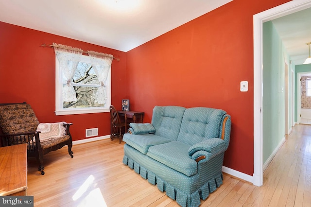 living area featuring visible vents, baseboards, and wood finished floors