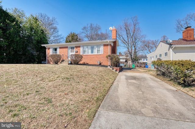 ranch-style house featuring a front lawn, brick siding, driveway, and a chimney