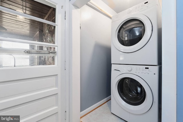 laundry area with laundry area, stacked washer and clothes dryer, and baseboards