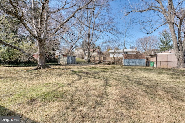 view of yard featuring a storage unit, an outdoor structure, and fence