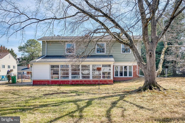 back of house featuring a gate, fence, a yard, a sunroom, and brick siding