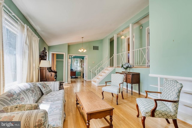 living room with visible vents, stairs, vaulted ceiling, an inviting chandelier, and wood finished floors