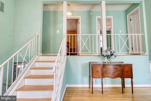 stairway with visible vents, baseboards, and wood finished floors