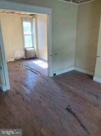 interior space with radiator, wood finished floors, and baseboards