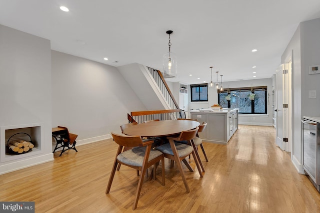 dining area featuring recessed lighting, baseboards, light wood-style floors, and wine cooler