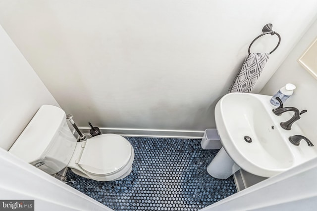 bathroom featuring toilet, baseboards, and a sink