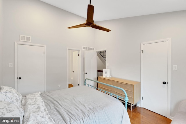 bedroom with visible vents, a high ceiling, and wood finished floors