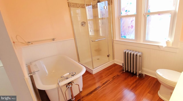 bathroom featuring toilet, a shower stall, radiator, and wood finished floors