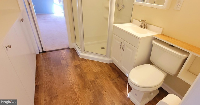 bathroom featuring wood finished floors, toilet, a stall shower, and vanity