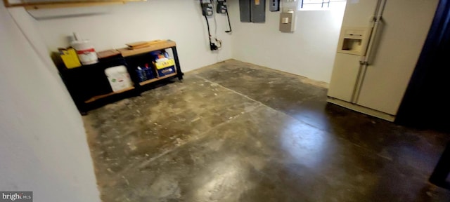 basement featuring electric panel and white fridge with ice dispenser