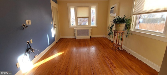 foyer with baseboards, a wall mounted AC, and hardwood / wood-style flooring