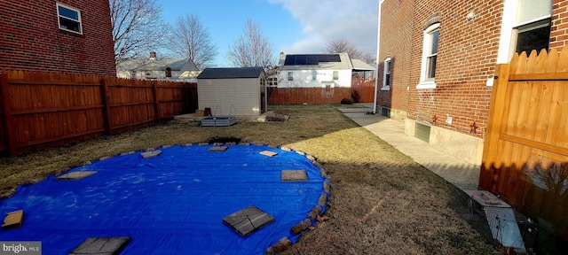 view of yard featuring a storage unit, a fenced backyard, and an outdoor structure