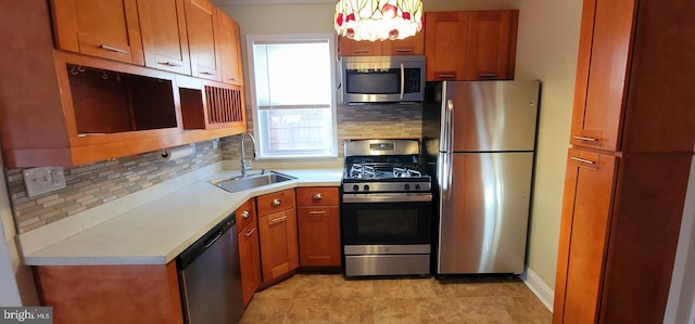 kitchen featuring brown cabinets, a sink, backsplash, appliances with stainless steel finishes, and light countertops