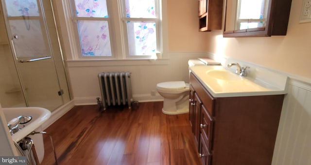 full bath featuring toilet, radiator heating unit, wood finished floors, an enclosed shower, and vanity