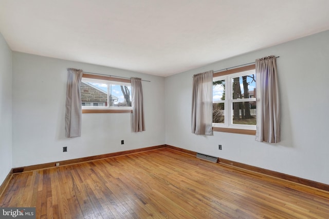 unfurnished room with visible vents, baseboards, and hardwood / wood-style flooring