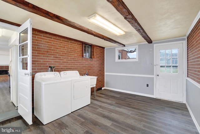 laundry area featuring laundry area, separate washer and dryer, brick wall, and wood finished floors