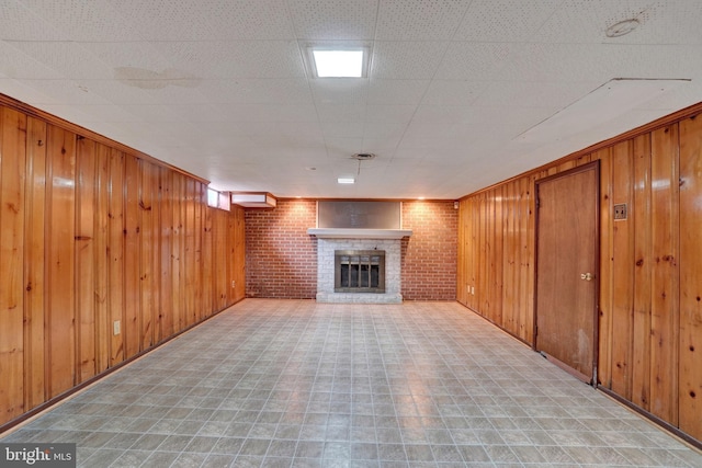 unfurnished living room with tile patterned floors, wooden walls, a fireplace, and brick wall