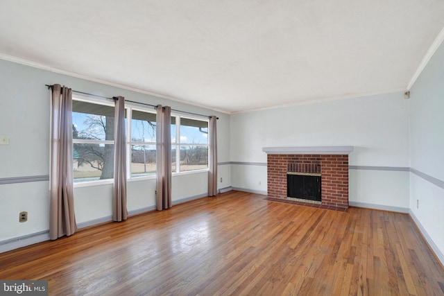 unfurnished living room featuring wood finished floors, baseboards, a fireplace, ornamental molding, and a baseboard heating unit