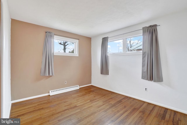 empty room featuring wood-type flooring, baseboards, and baseboard heating