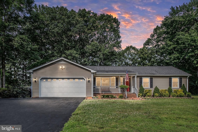 single story home featuring driveway, a lawn, covered porch, and an attached garage