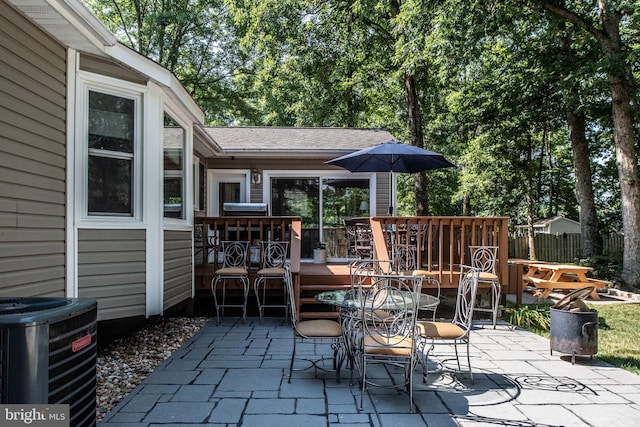 view of patio with central AC unit, outdoor dining space, and fence