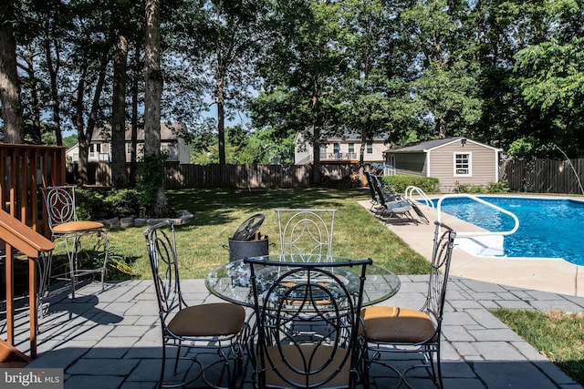 view of pool with a yard, a fenced backyard, a patio area, outdoor dining space, and an outbuilding