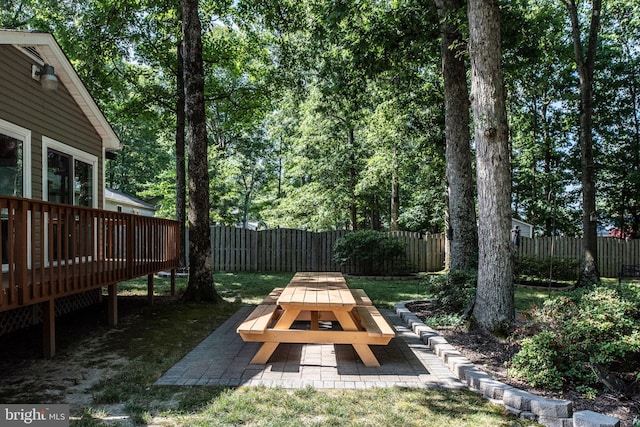 view of yard with outdoor dining space, a patio area, a fenced backyard, and a wooden deck