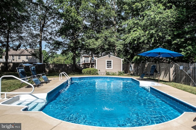 view of swimming pool featuring a patio area, a fenced backyard, a fenced in pool, and an outbuilding