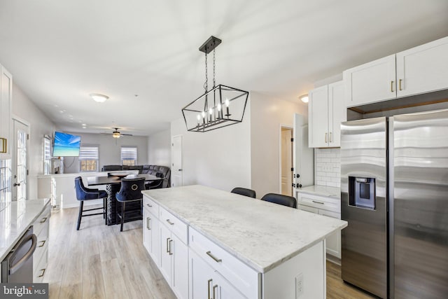 kitchen featuring a center island, decorative backsplash, appliances with stainless steel finishes, light wood-style floors, and a ceiling fan