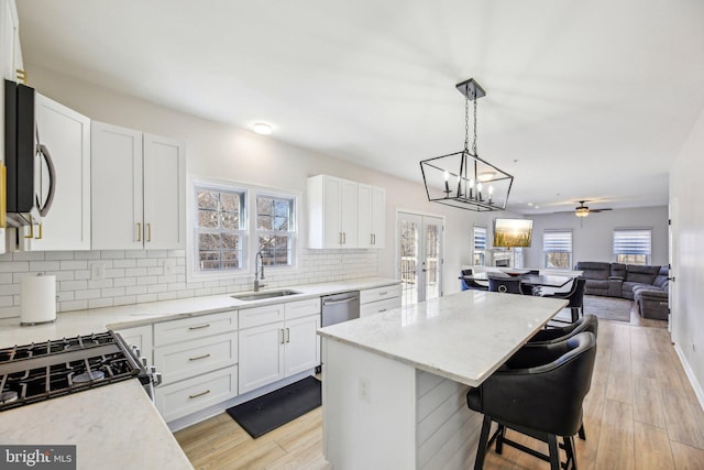 kitchen with a breakfast bar, a sink, open floor plan, a center island, and appliances with stainless steel finishes