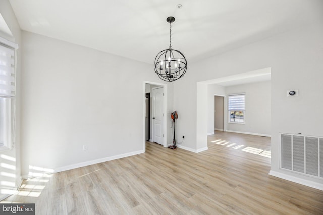 interior space featuring light wood-type flooring, visible vents, baseboards, and a notable chandelier