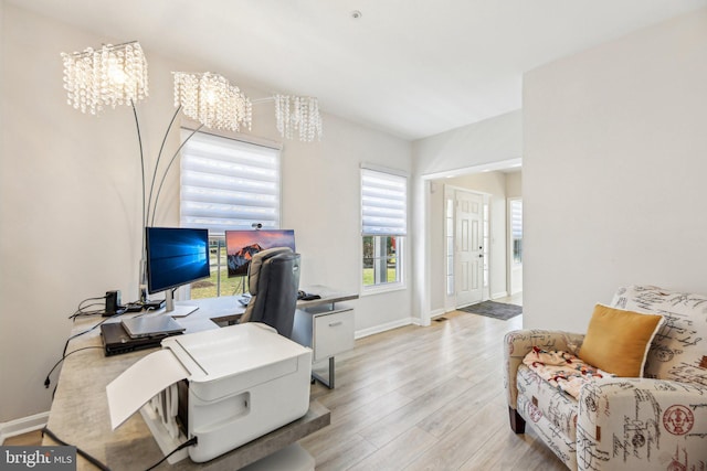 office area with light wood finished floors, a notable chandelier, and baseboards