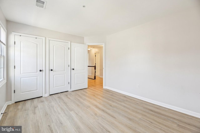 unfurnished bedroom featuring visible vents, baseboards, a closet, and light wood-style flooring