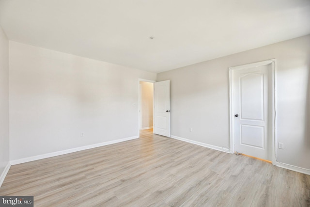 spare room featuring baseboards and light wood-style flooring