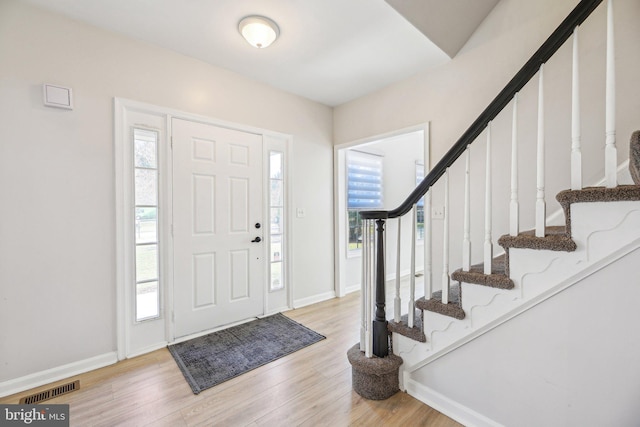 entryway featuring stairs, baseboards, visible vents, and light wood finished floors