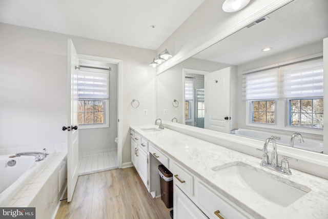 bathroom featuring a sink, a garden tub, double vanity, and toilet