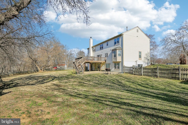 rear view of house featuring a deck, stairs, fence, a yard, and a chimney