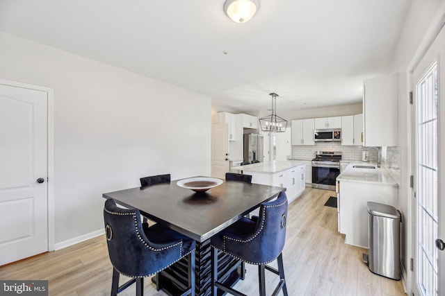 dining area featuring a notable chandelier, light wood-type flooring, and baseboards