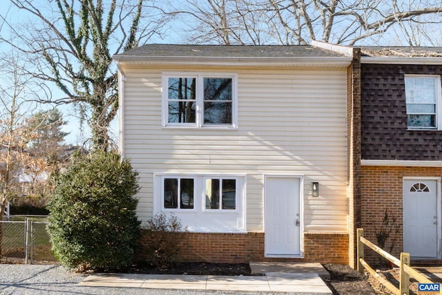 view of front of property featuring brick siding, a shingled roof, and fence