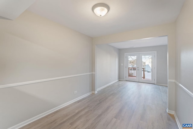 spare room with wood finished floors, baseboards, and french doors