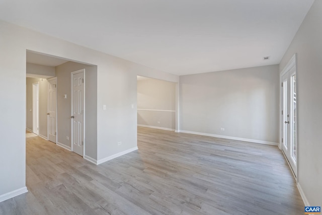 spare room with baseboards and light wood-type flooring