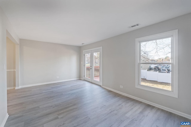 spare room with visible vents, french doors, baseboards, and wood finished floors