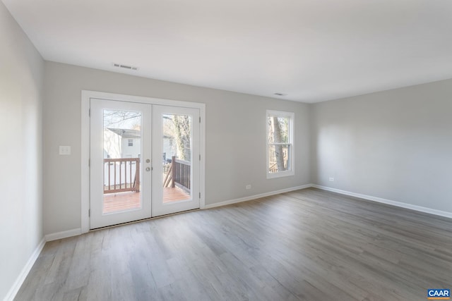 unfurnished room featuring a wealth of natural light, visible vents, wood finished floors, and french doors